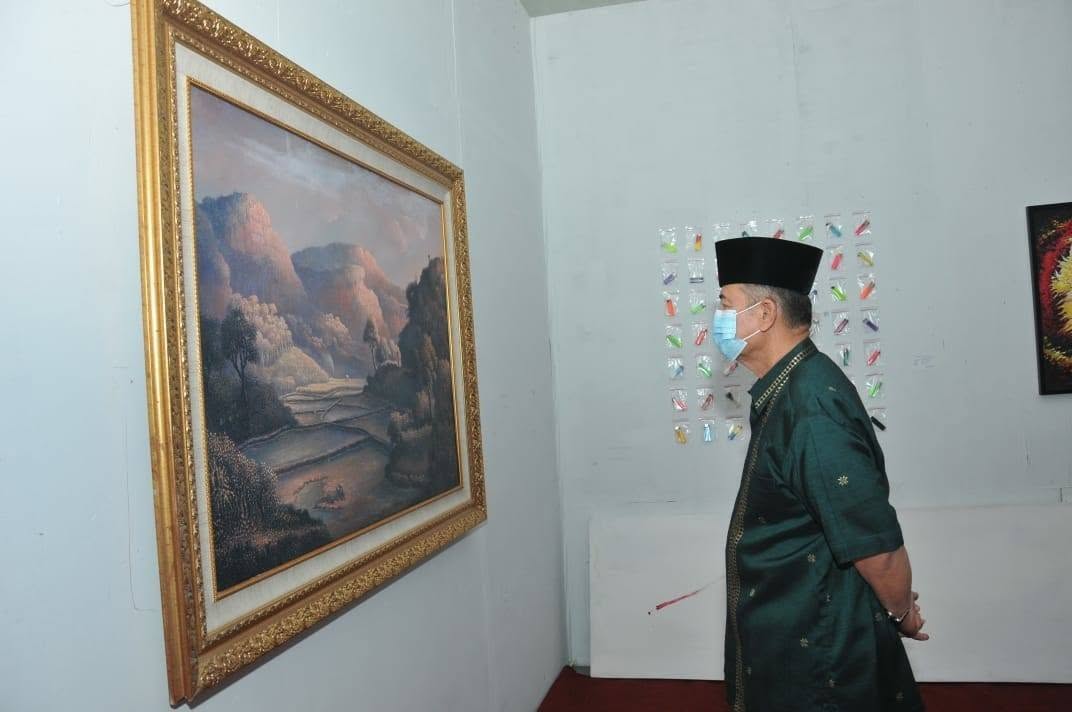 Nasrul Abit mengamati dengan serius salah lukisan pameran di Galeri Taman Budaya Sumbar (2020)
