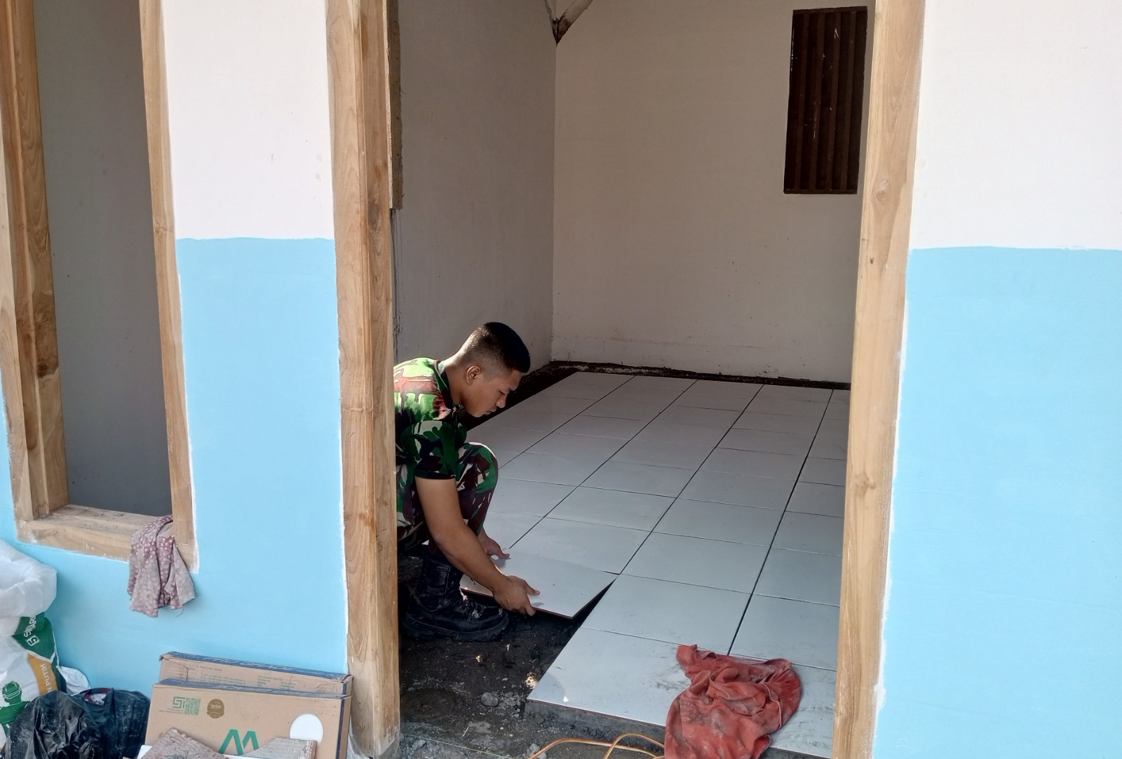 Wujudkan Impian Rumah Layak Huni, Satgas TMMD ke-129 Kodim 0813 Bojonegoro dan Warga Gotong Royong Pasang Keramik di Rumah Ibu Tini